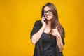 Portrait of young woman talking on cellphone showing thumb up sign, over yellow background Royalty Free Stock Photo