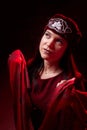 Portrait of a young beautiful woman in Tatar national folk red hat and a red dress. Fashion photo shoot in low key Royalty Free Stock Photo