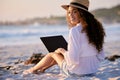 This place is perfect for anything. Portrait of a young beautiful woman using a laptop while sitting at the beach. Royalty Free Stock Photo