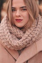 Portrait of young beautiful woman walking in stylish warm outfit in sunny autumn day in park, wearing pink coat and knitted snood Royalty Free Stock Photo