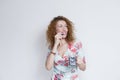 Portrait of a young beautiful woman wearing a colorful flowers dress over white background. She is smiling and holding a jug of Royalty Free Stock Photo