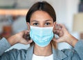 Young beautiful woman wearing an hygienic mask to prevent others from a virus while looking at camera in the home