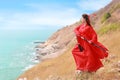 Portrait of young and beautiful woman wearing red chinese warrior costume with black sword, she post using sword on moutain with Royalty Free Stock Photo