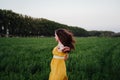 Portrait of young beautiful woman wearing a yellow dress running in a green field. Summertime and lifestyle Royalty Free Stock Photo