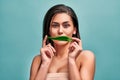 Portrait of a young beautiful woman who holds a leaf of aloe vera and hides a smile. The concept of cosmetics and facial and body