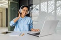 Portrait of young beautiful woman at workplace inside office, businesswoman programmer in headphones smiling and looking Royalty Free Stock Photo