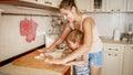 Portrait of young beautiful woman teaching her little child boy making cookies and baking pies on kitchen at home Royalty Free Stock Photo