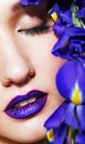 Portrait of young beauty female face with violet lips makeup and irist flowers near face Royalty Free Stock Photo