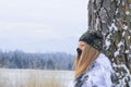 Portrait a young beutiful hunter woman , she is wearing winter camouflage . In the background are snowy trees. Banner photo