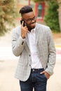 Young black businessman with glasses walking outside and talking on mobile phone Royalty Free Stock Photo