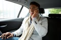 Young black businessman sitting ion backseat of car and talking with cellphone Royalty Free Stock Photo