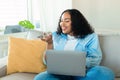 Portrait of young black chubby woman using laptop and talking on speakerphone, dictating voice message