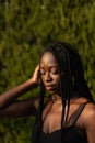 Portrait of a young black female removing her hair from her face whit her eyes closed