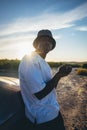 Portrait of a young black handsome man wearing a bucket hat posing outside by his car at sunset Royalty Free Stock Photo