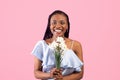 Portrait of young black lady with bouquet of narcissus flowers over pink studio background Royalty Free Stock Photo