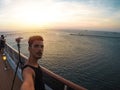 Portrait of a young black male tourist on the deck of a cruise ship in front of a sunset sky. African tourist on the beach trip Royalty Free Stock Photo