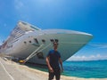 Portrait of a young black male tourist in front of a cruise ship on cloudy sky. African tourist on the beach trip Royalty Free Stock Photo