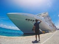 Portrait of a young black male tourist in front of a cruise ship on cloudy sky. African tourist on the beach trip Royalty Free Stock Photo