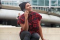 Young black man smiling in city and talking with smart phone Royalty Free Stock Photo