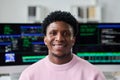 Portrait of Young Black Man Smiling in Front of Computer Screens Royalty Free Stock Photo