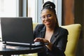 Portrait of a young black woman smiling and using laptop Royalty Free Stock Photo