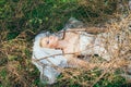 Portrait of young blond bride with veil that lies on earth under the branches