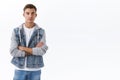 Portrait of young blond caucasian guy in denim jacket standing over white background with normal expression, looking