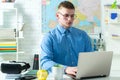 Portrait of young blond caucasian student in school. Handsome college boy using laptop. Caucasian male student in Royalty Free Stock Photo