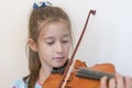 Portrait of a young blond teenage girl playing violin. Girl playing the violin on a light background. Royalty Free Stock Photo