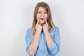 Portrait of young blond upset woman fixing her lips up with fingers pretending happy on isolated white background, body language