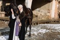 Portrait of a young blond woman in a black cloak with a horse. Royalty Free Stock Photo