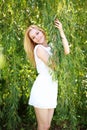 Portrait of a young blond woman in green willow tree Royalty Free Stock Photo