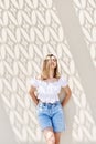 Portrait of a young blond woman standing near wall with beautiful shadows Royalty Free Stock Photo