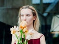 Portrait of the young blonde attractive woman with the iris flowers behind the glass Royalty Free Stock Photo