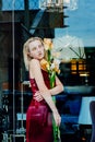 Portrait of the young blonde attractive woman with the iris flowers behind the glass Royalty Free Stock Photo