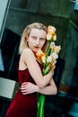 Portrait of the young blonde attractive woman with the iris flowers behind the glass Royalty Free Stock Photo