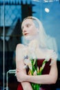 Portrait of the young blonde attractive woman with the iris flowers behind the glass Royalty Free Stock Photo