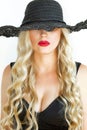 Portrait of a young blonde in a black hat with Decollete, on white background. Close-up. Royalty Free Stock Photo