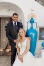 Portrait of young blonde bride in white dress and brunet groom in suit smiling and sitting near old city house with Royalty Free Stock Photo