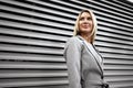 Portrait of young blonde businesswoman in gray suit walking in the city Royalty Free Stock Photo