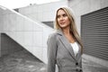 Portrait of young blonde businesswoman in gray suit walking in the city Royalty Free Stock Photo