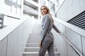 Portrait of young blonde businesswoman in gray suit walking in the city Royalty Free Stock Photo