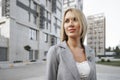 Portrait of young blonde businesswoman in gray suit walking in the city Royalty Free Stock Photo