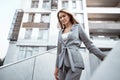 Portrait of young blonde businesswoman in gray suit walking in the city Royalty Free Stock Photo