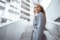Portrait of young blonde businesswoman in gray suit walking in the city Royalty Free Stock Photo