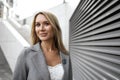 Portrait of young blonde businesswoman in gray suit walking in the city Royalty Free Stock Photo