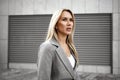 Portrait of young blonde businesswoman in gray suit walking in the city Royalty Free Stock Photo