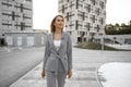 Portrait of young blonde businesswoman in gray suit walking in the city Royalty Free Stock Photo