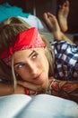 Portrait of a young blonde closeup. Distracted from reading and looking wistfully out the window. Wears a red headband