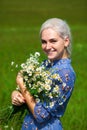 Portrait of a young blonde girl with a bouquet of chamomile in a field